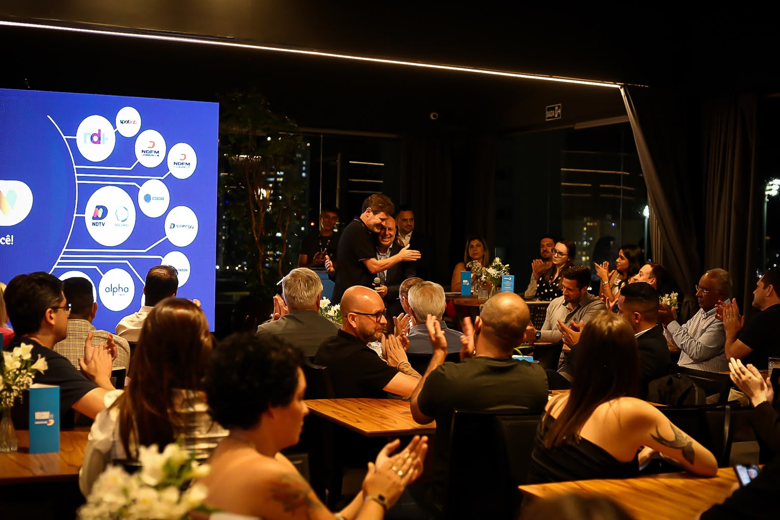 Convidados aplaudindo durante evento no salão
